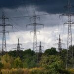 Ciemne burzowe niebo nad liniami energetycznymi - ilustracja do artykułu o rekordowym tygodniu cen energii