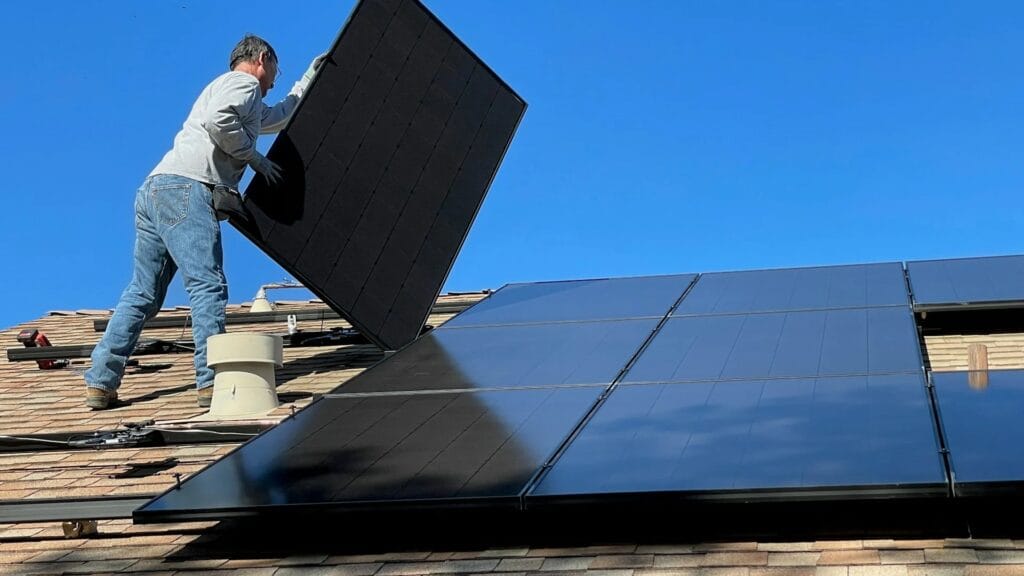 Instalator mocujący panel fotowoltaiczny na dachu domu - rozbudowa istniejącej instalacji PV o magazyn energii