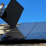 Instalator mocujący panel fotowoltaiczny na dachu domu - rozbudowa istniejącej instalacji PV o magazyn energii